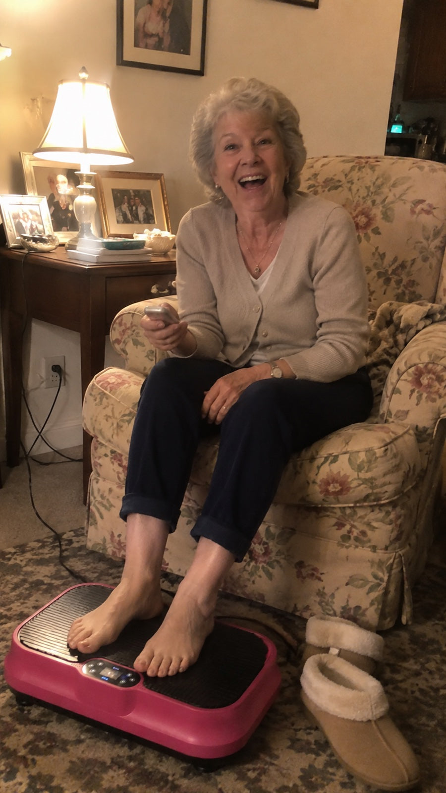 Woman laughing in her floral armchair with both feet resting on the pink Nuvé plate, remote in hand