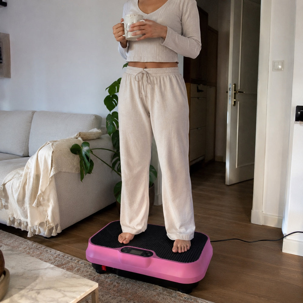 Woman in pajamas standing on the pink Nuvé plate in her living room, mug in hand