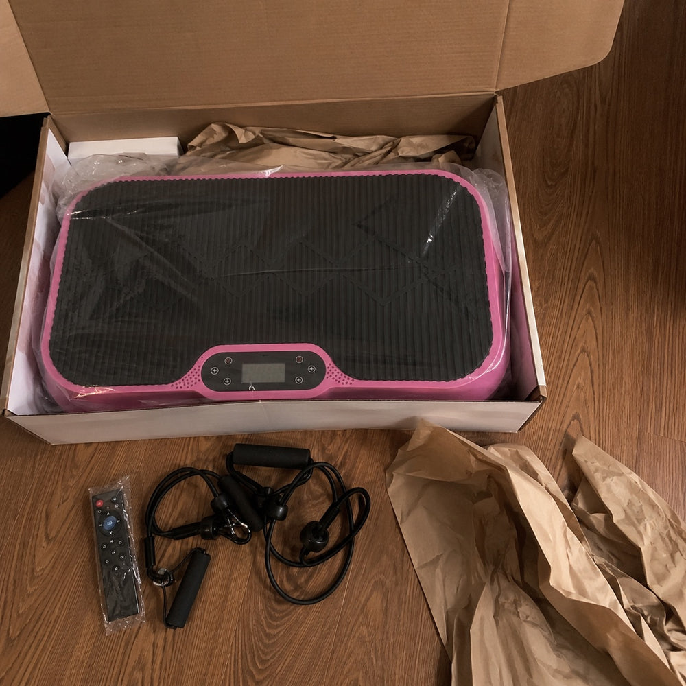 The pink Nuvé plate just unboxed, with the remote and resistance bands laid out on the floor